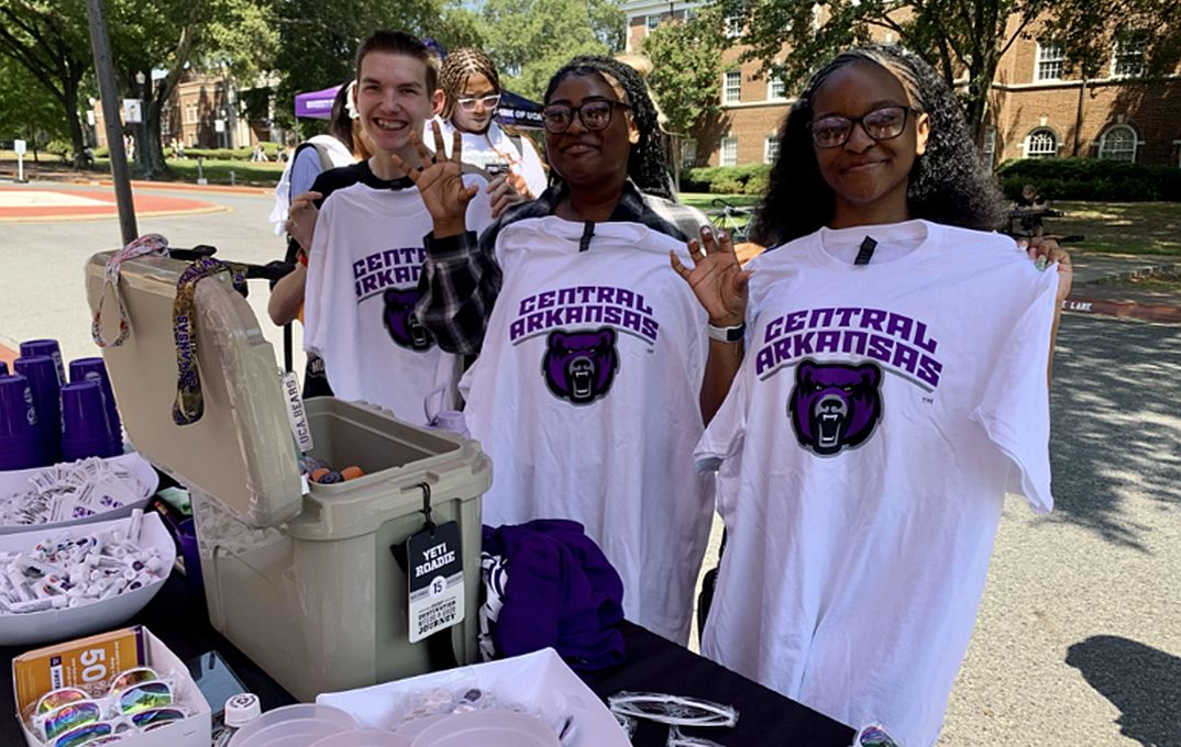 3 college students holding T-shirts